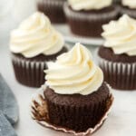 A chocolate cupcake recipe with one having the wrapper down and several in the white background