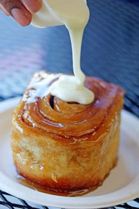 Cream poured over a warm and gooey cinnamon roll at Cinnamon Roll Place