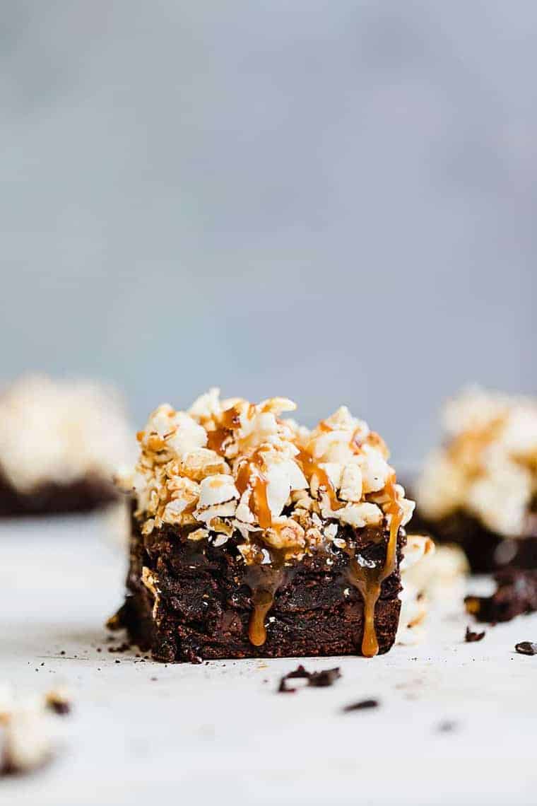 Close up of a Salted Caramel Popcorn Brownie with more brownies in the background and out of focus