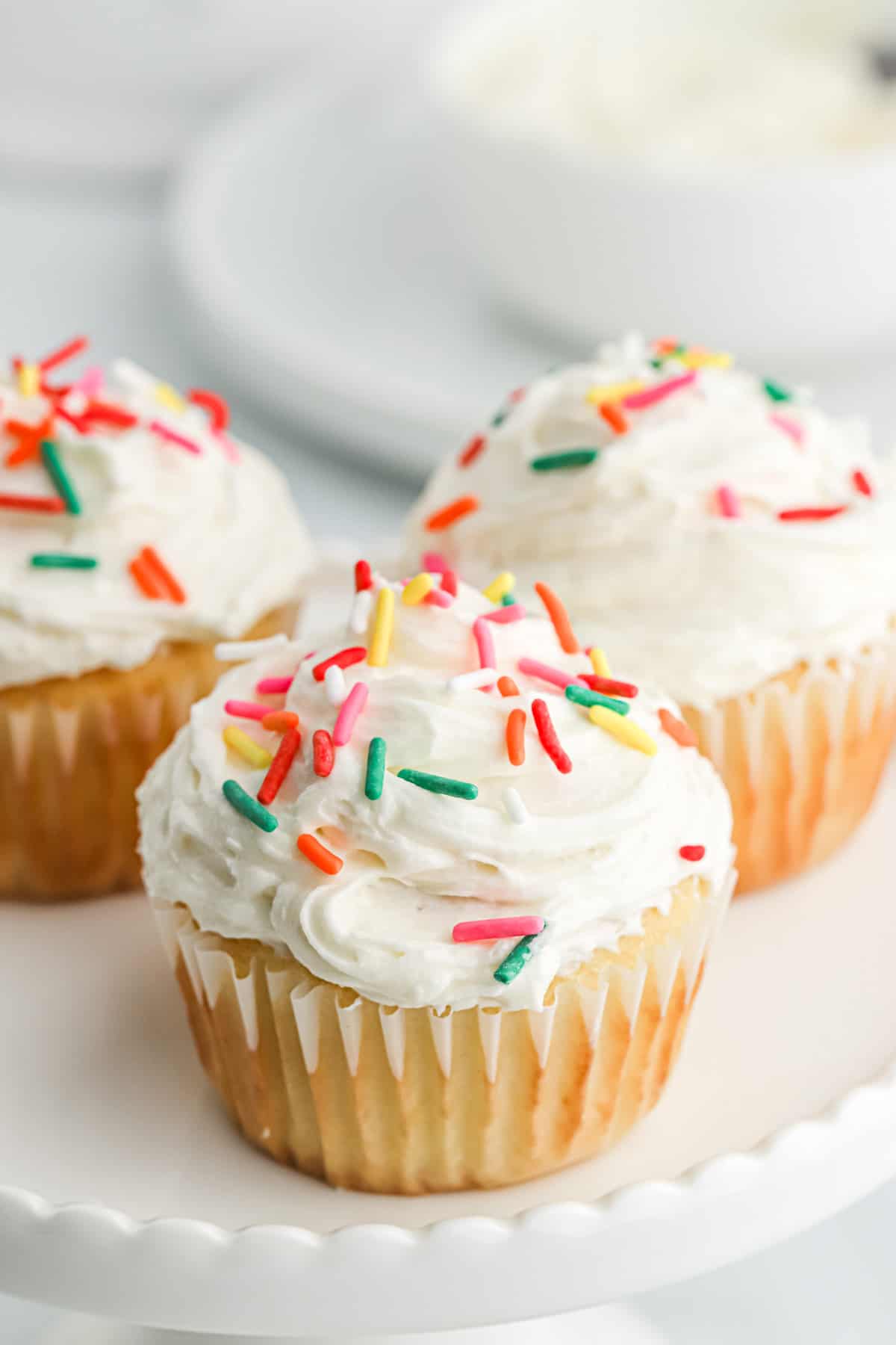 Cupcakes topped with American buttercream and sprinkles on the table.