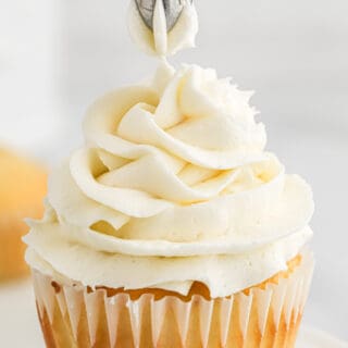 Piping a cupcake with American buttercream frosting.