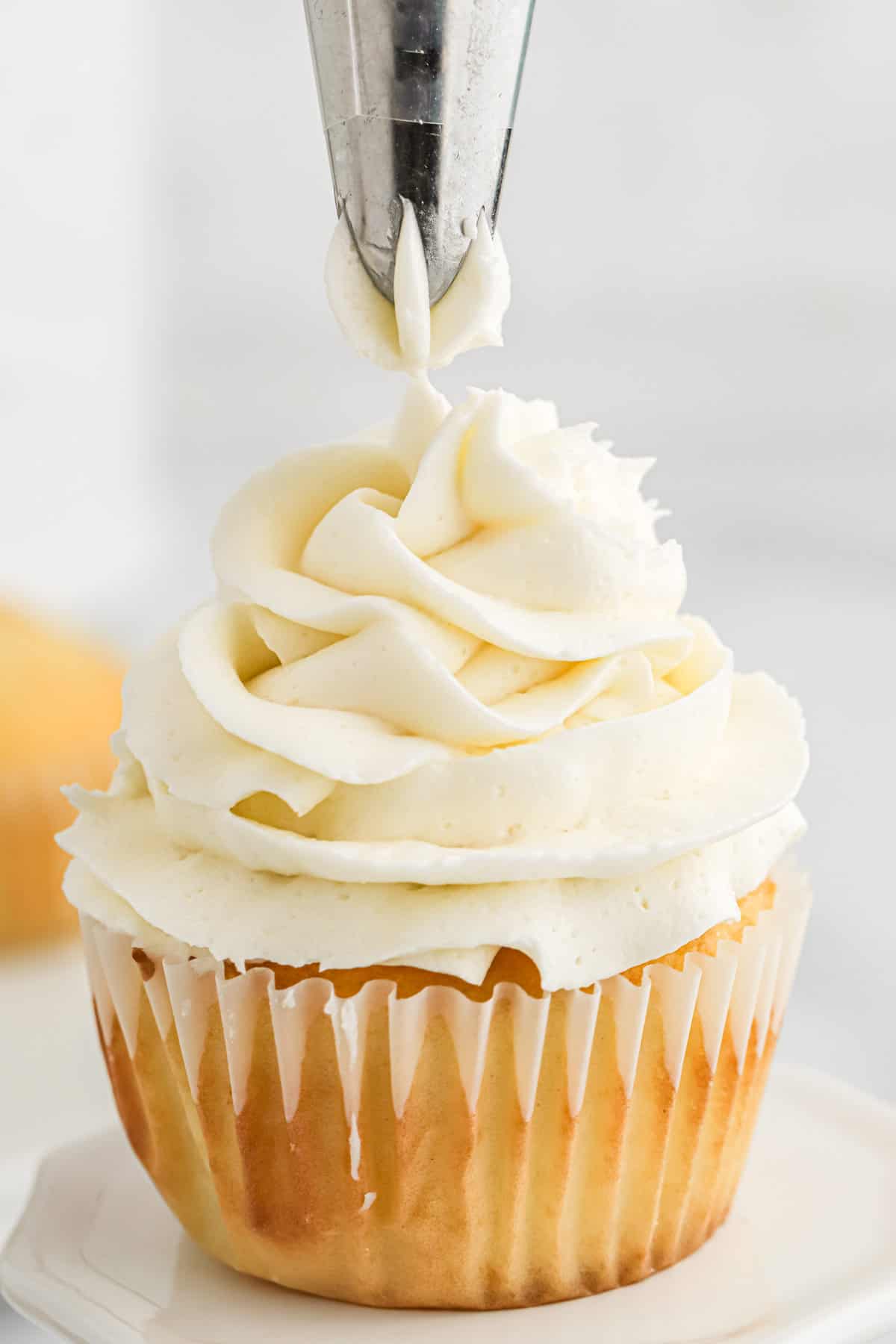 Piping a cupcake with American buttercream frosting.