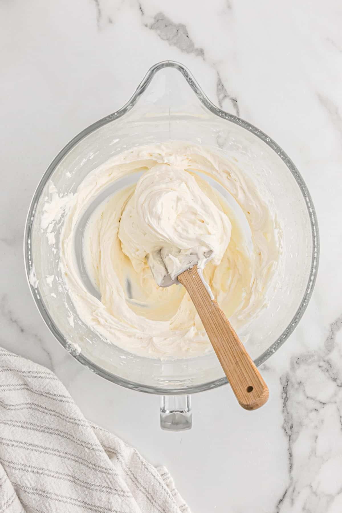 American buttercream in a mixing bowl with a wooden spoon.