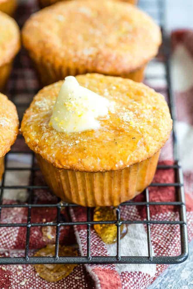 A close up of this Corn Muffin recipe on wire rack with melted butter