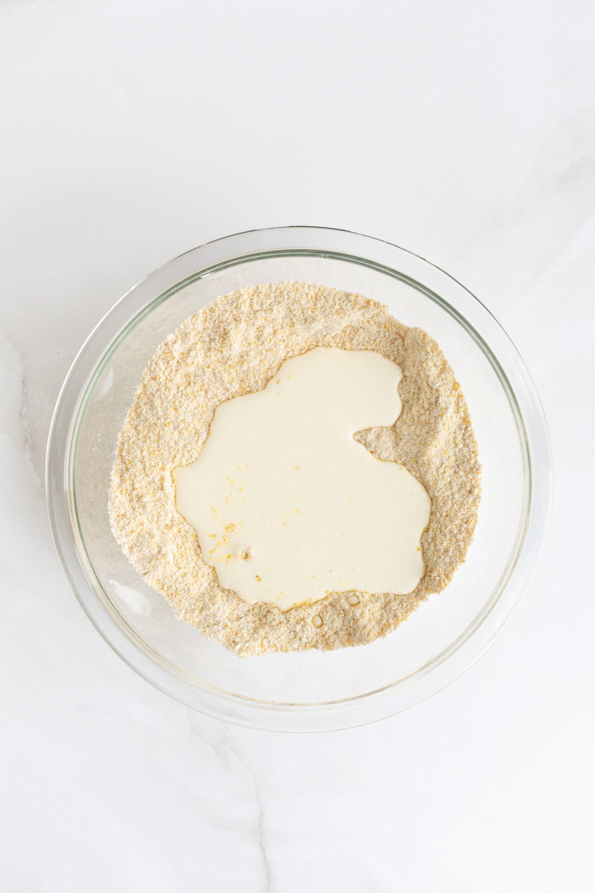 Wet mixture poured into the center of dry ingredients in a glass bowl