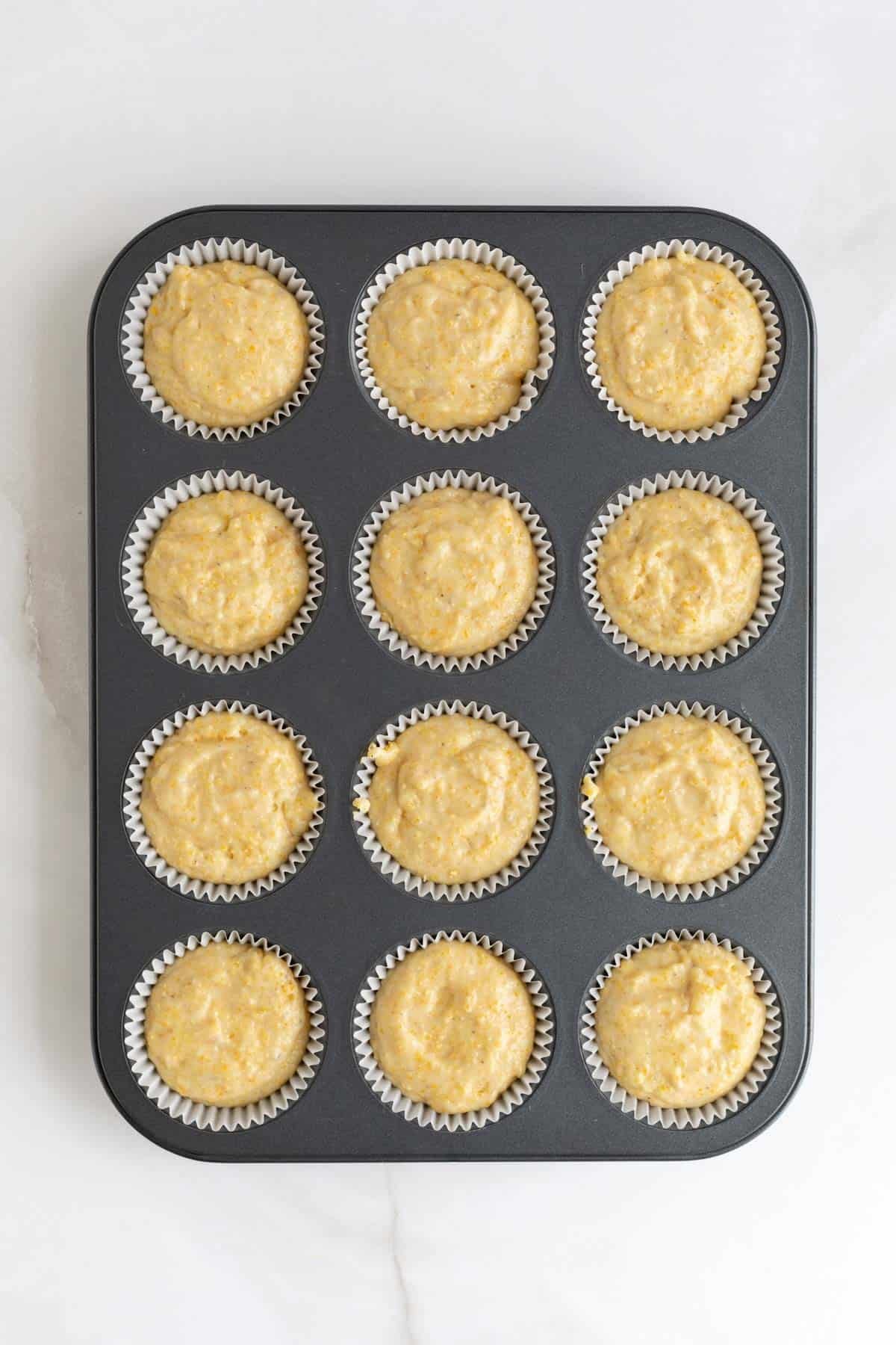 Muffin batter scooped into the lined muffin tin, ready to bake