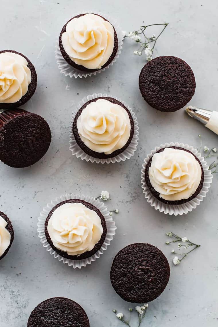 Best Chocolate Cupcake Recipe on display with several cupcakes some topped with buttercream frosting and some with no frosting. 