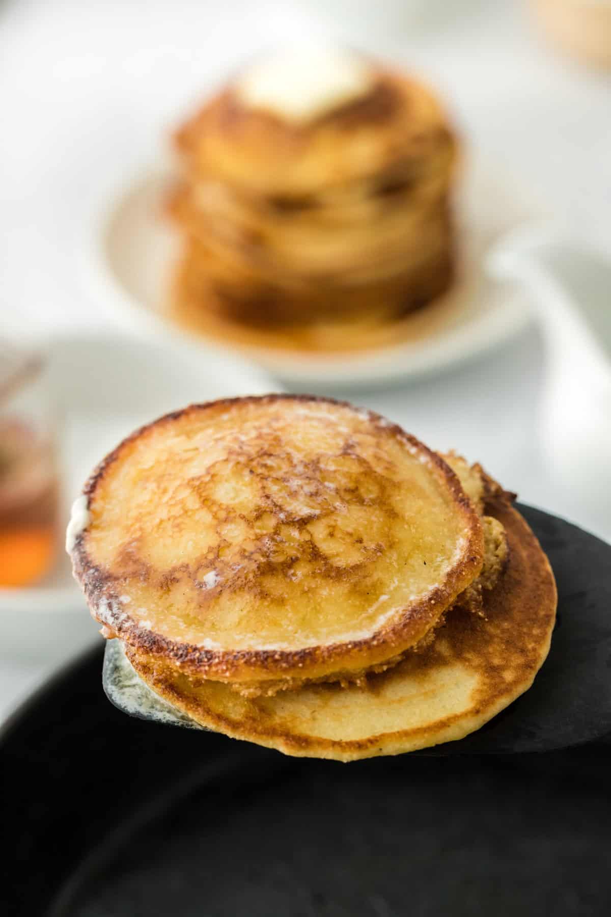 Johnny cakes on spatula to share coming out of the skillet