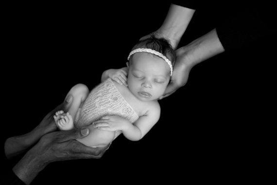 Black and white photo of a sleeping Harmony being held by her parents