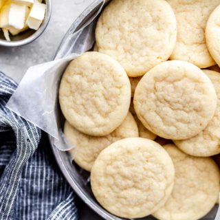 Overhead of Southern Tea Cakes in a tin against light gray background with butter in small bowl