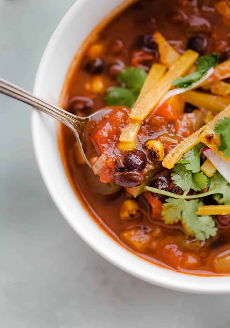 Close up of a cup of Chipotle Black Bean vegetarian Tortilla Soup with a spoon in it