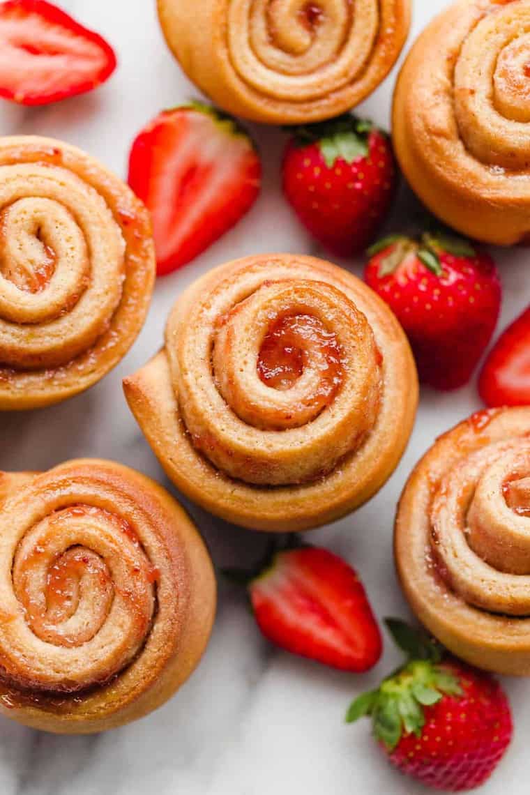 Overhead shot of Strawberry Butter Rose Buns with whole fresh strawberries surrounding them. 
