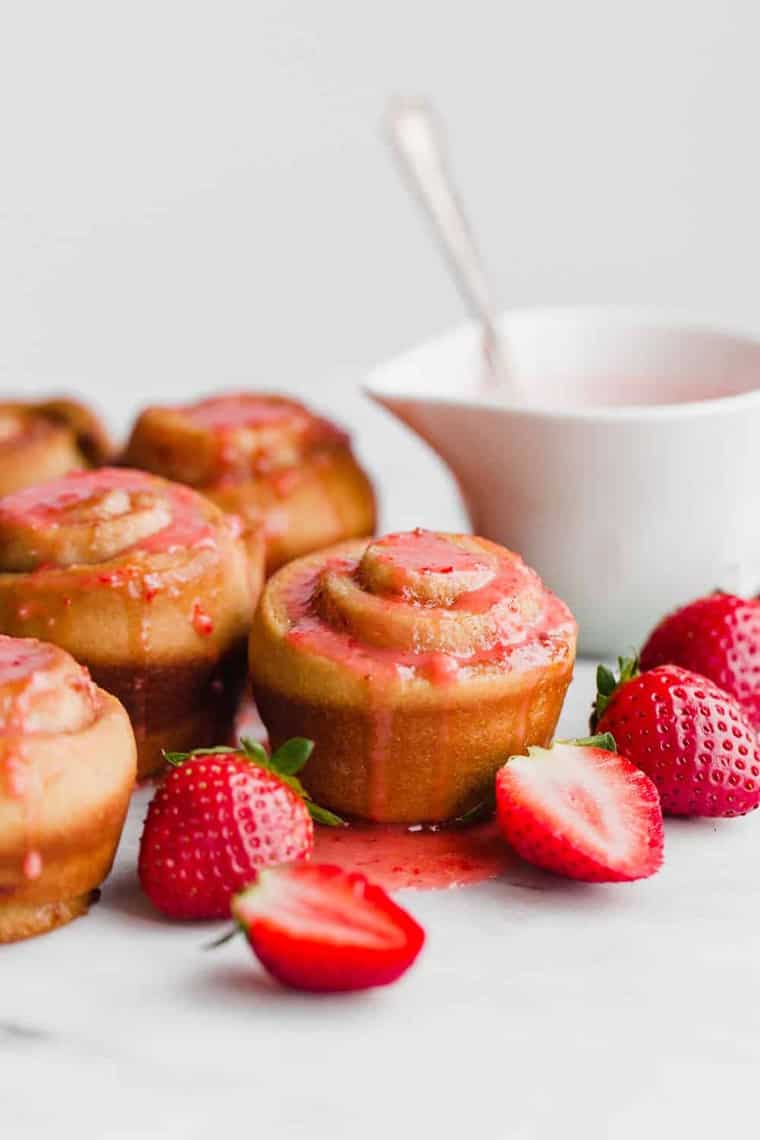 Strawberry Butter Rose Buns topped with strawberry sauce next to fresh strawberries