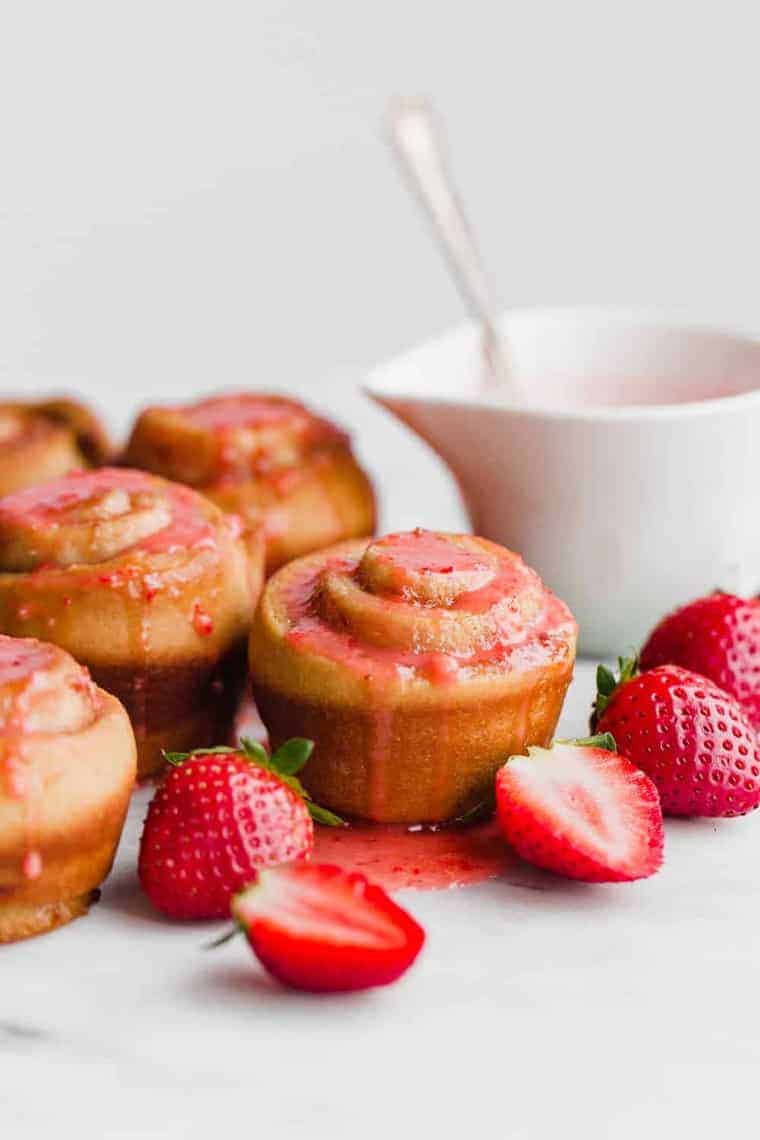 Strawberry Butter Rose Buns topped with strawberry sauce next to fresh strawberries