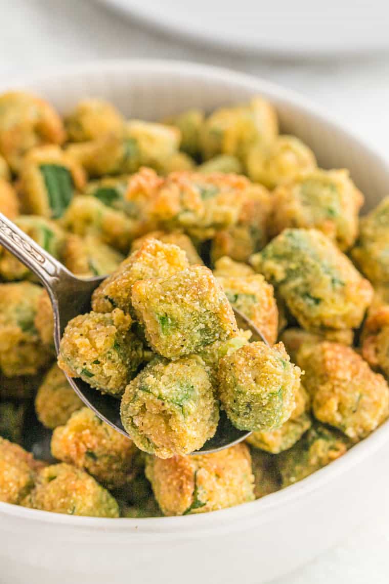 A close up of fried okra on a spoon before serving