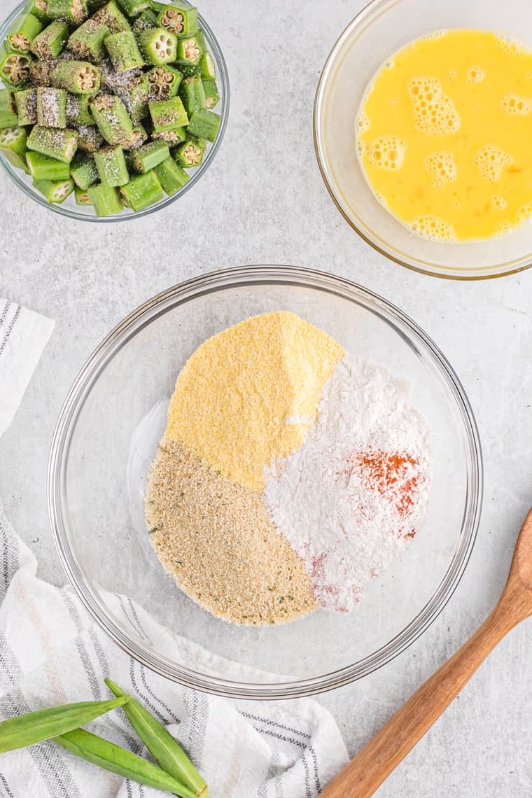 Cornmeal, flour, breadcrumbs and spices in a clear bowl before breading okra