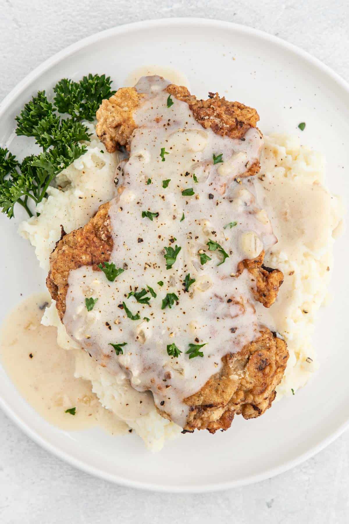 A plate of a chicken fried steak recipe served over mashed potatoes with gravy