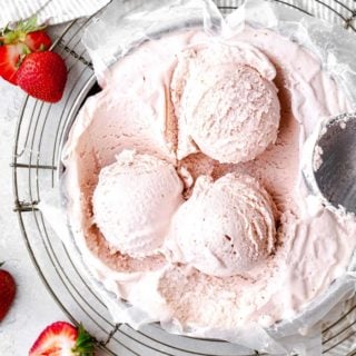 Overhead photo of three scoops of homemade strawberry ice cream against white background