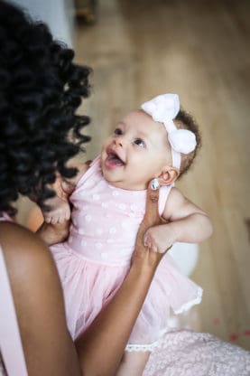 Baby Cakes Harmony laughing and looking up at Jocelyn, whose back is facing the camera