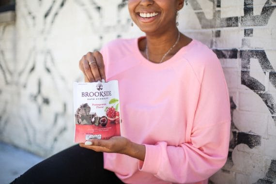 Jocelyn holding one pack of Brookside chocolates