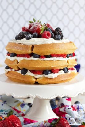Berry and Cream Waffle Cake presented on a white cake plate 