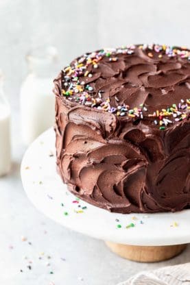 A chocolate birthday cake covered with sprinkles against a white background