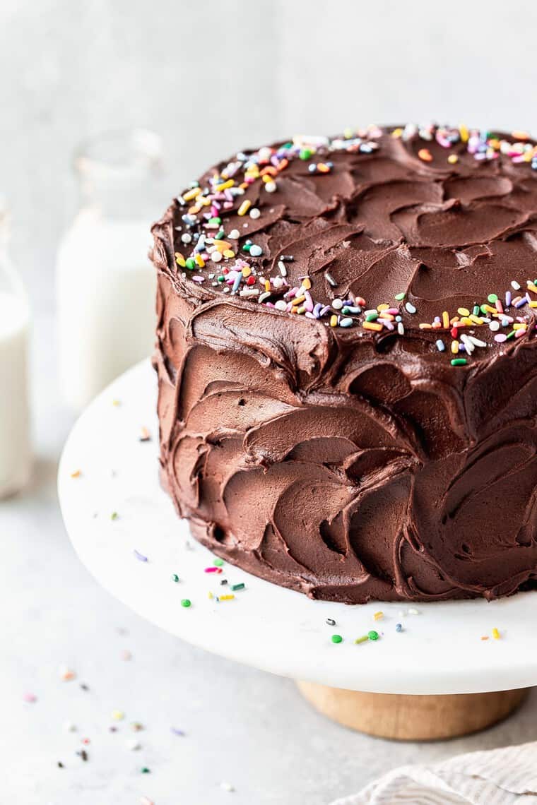 A chocolate birthday cake covered with sprinkles against a white background