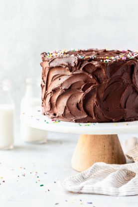 Chocolate frosting on a birthday cake on a cake stand against white background