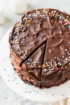 Overhead of chocolate birthday cake with sprinkles with a slice of cake