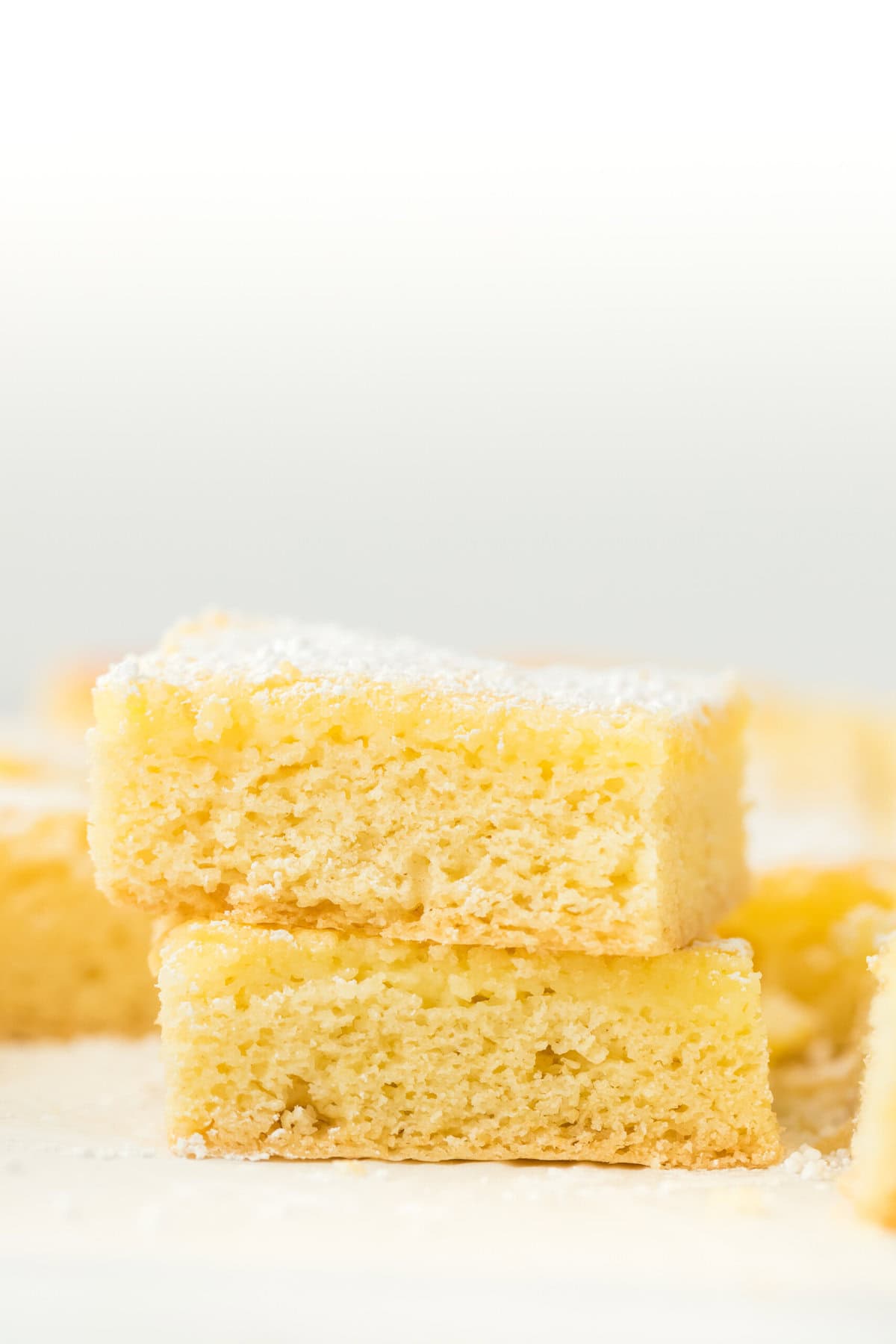 Slices of St. Louis gooey butter cake stacked on top of each other in white background