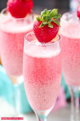 Close up of Strawberry Cream Mimosas with one fresh strawberry on the rim of each wine glass