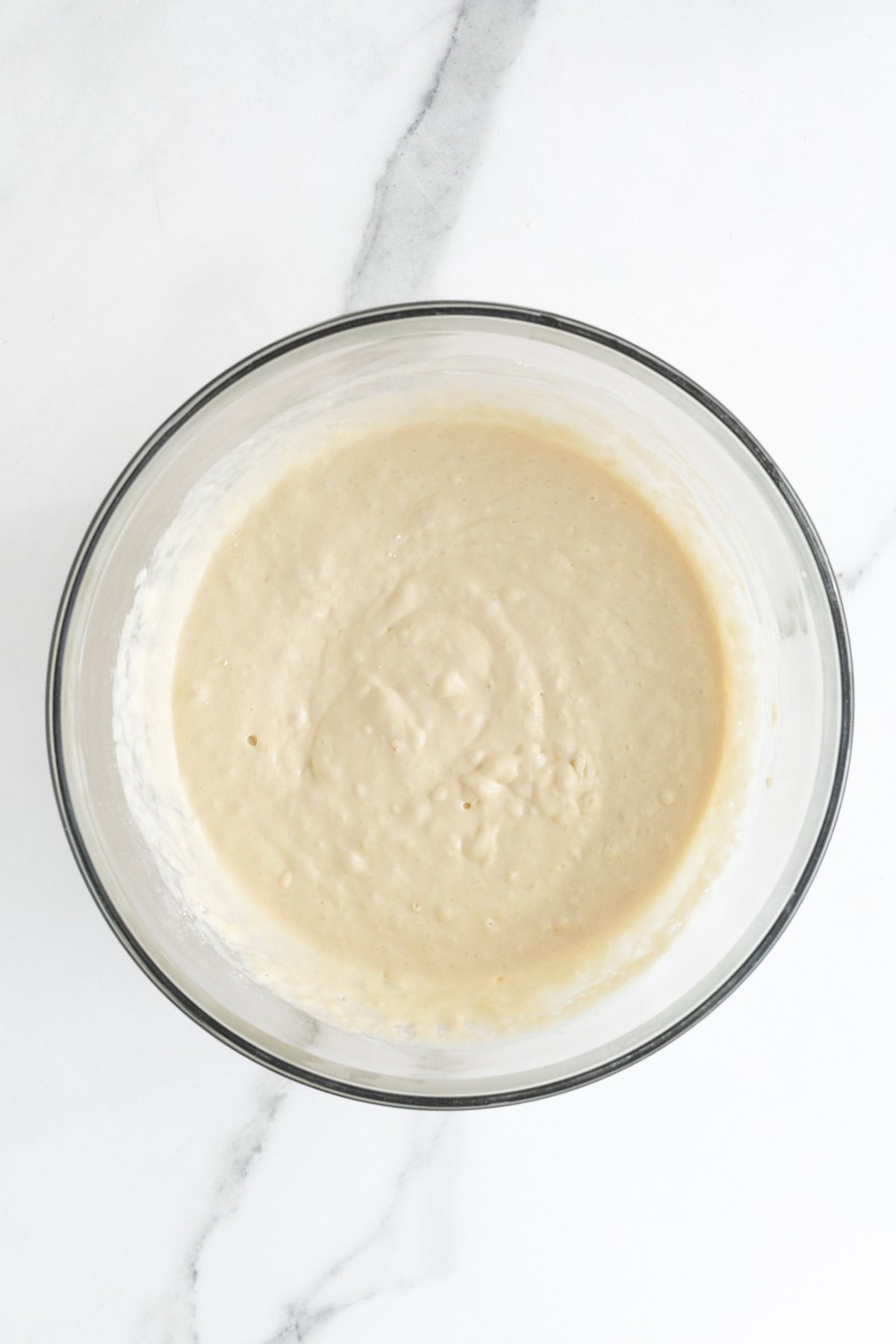 Pancake batter after combining in a glass bowl on white countertop