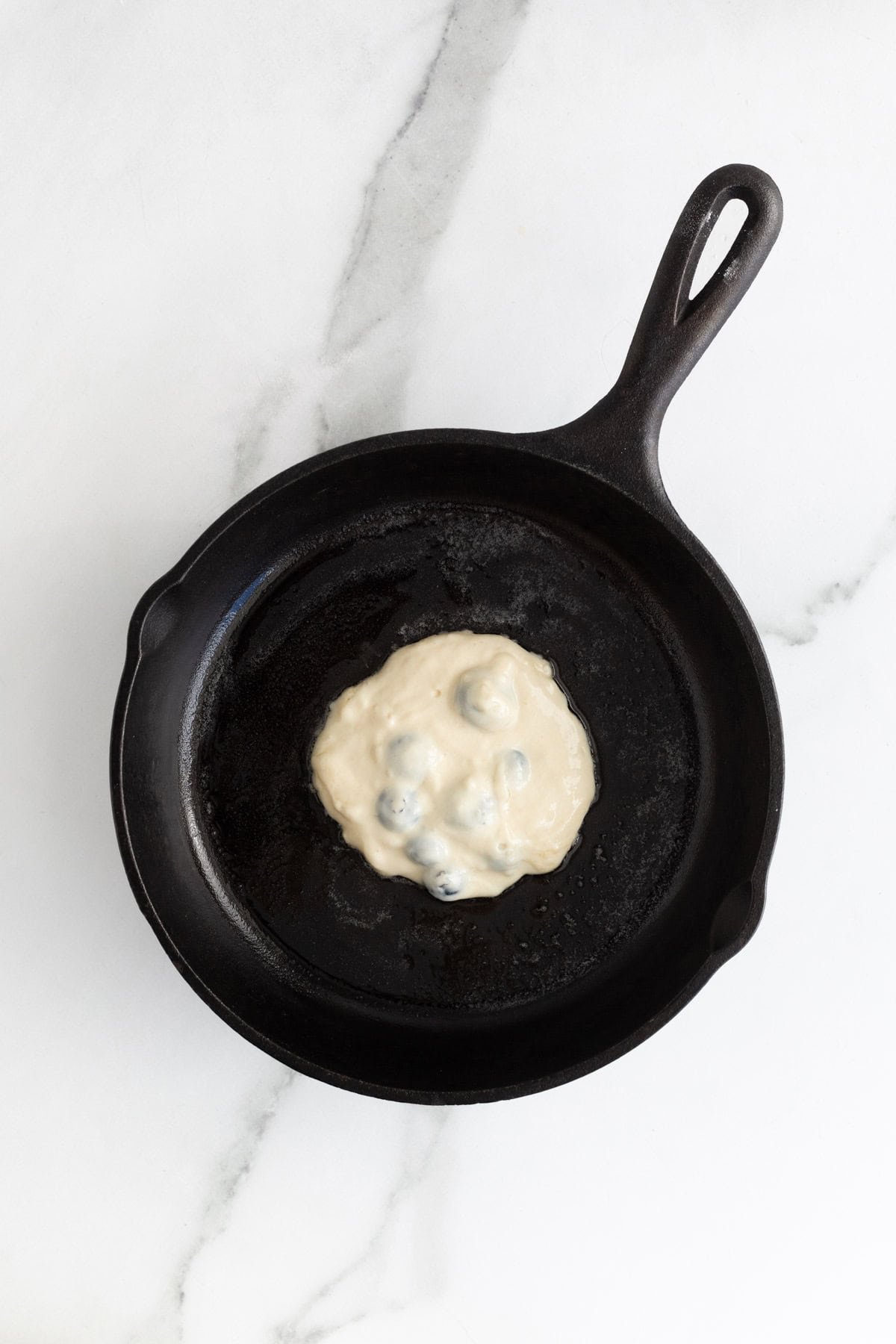 Blueberry pancake batter on a cast iron skillet