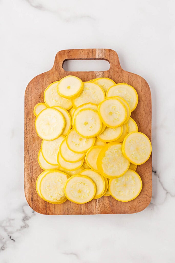 Sliced yellow squash on a wooden cutting board