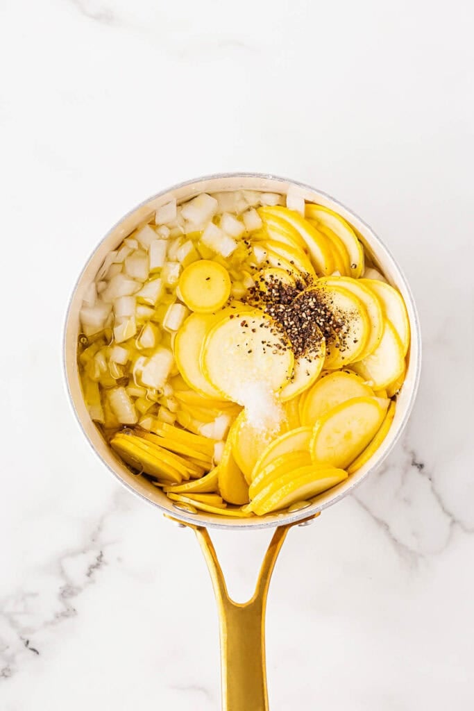 Yellow squash in a pot along with seasoning and onion and water