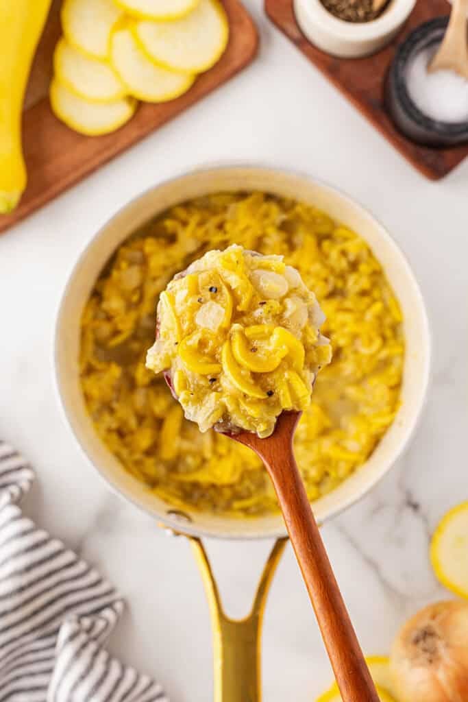 Sauteed yellow squash being lifted from a pot
