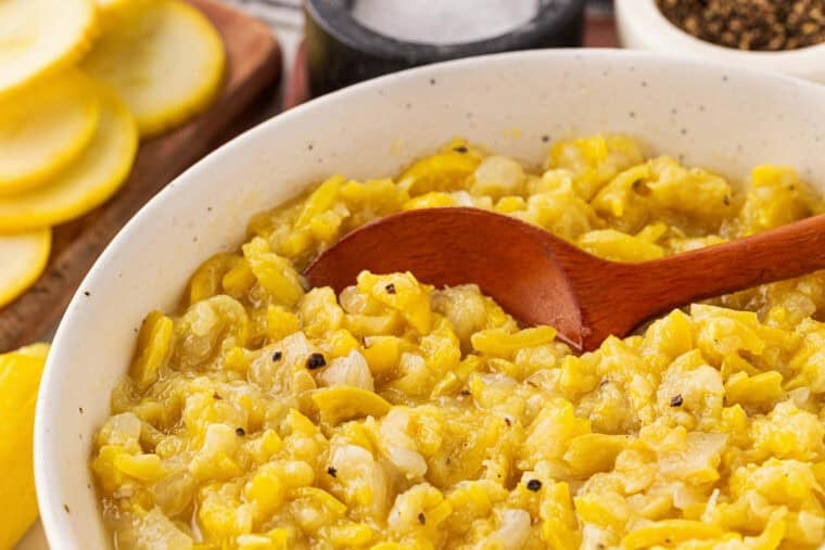 A close up of sauteed yellow squash in a white bowl
