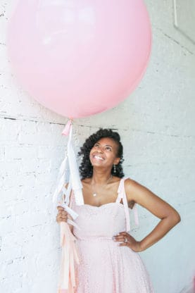 Jocelyn holding and looking up at a large pink balloon