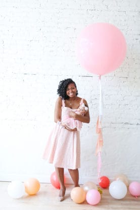 Jocelyn standing and holding her daughter with balloons surrounding her