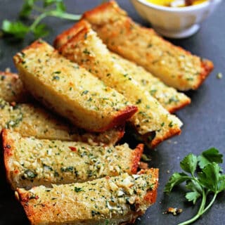 Slices of garlic bread ready to enjoy with parsley in background