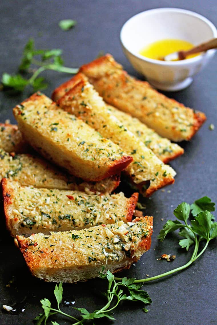 Slices of garlic bread ready to enjoy with parsley in background
