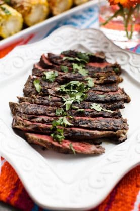 A white tray of carved grilled skirt steak prepared medium well done