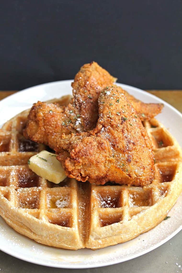 A top down shot of Southern chicken and waffles with butter and syrup melting down with a black background