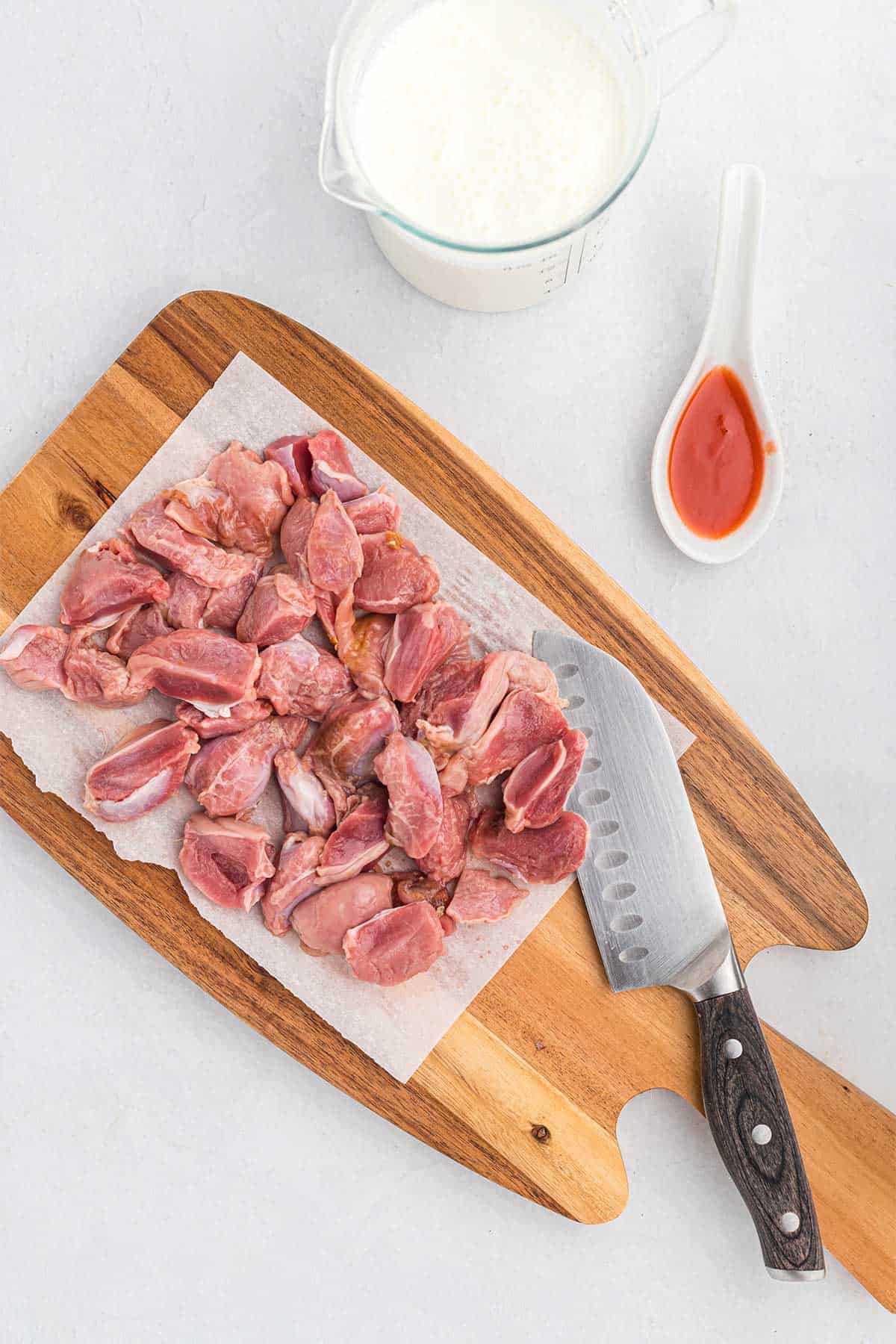 Trimmed chicken gizzards on a cutting board with a knife.