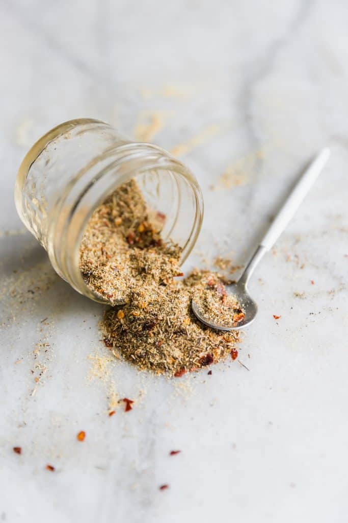 Jamaican Jerk Seasoning falling out of a glass with a spoon