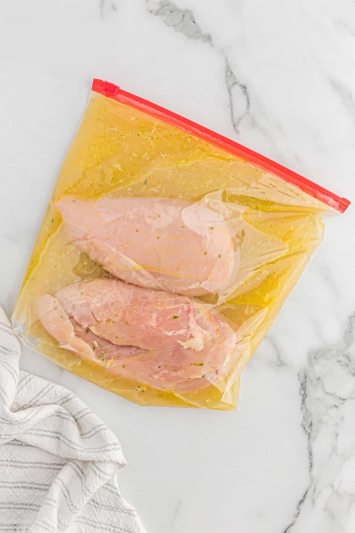 Chicken breasts and marinade in a plastic bag.