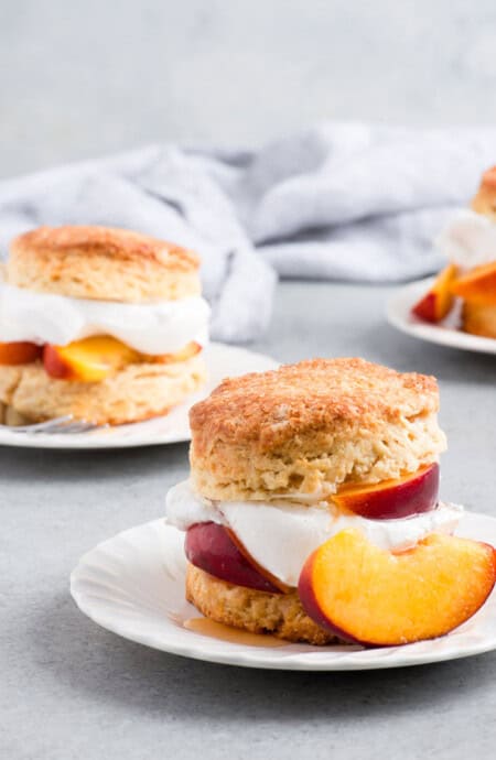Peach Shortcake Recipe- Buttery flaky shortcake biscuits get topped with brown sugar soaked ripe peaches and fluffy whipped cream for the ultimate summer delight. #peach #peaches #shortcake #biscuits