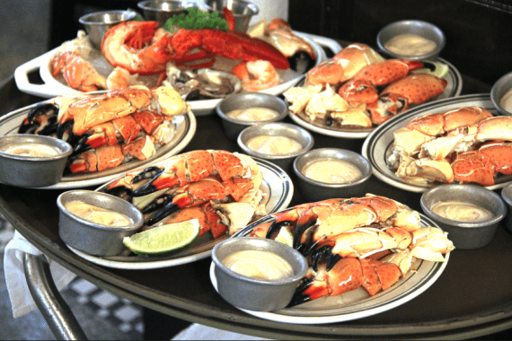 A black tray full of plates of stone crabs at Joe's Stone Crab in Miami