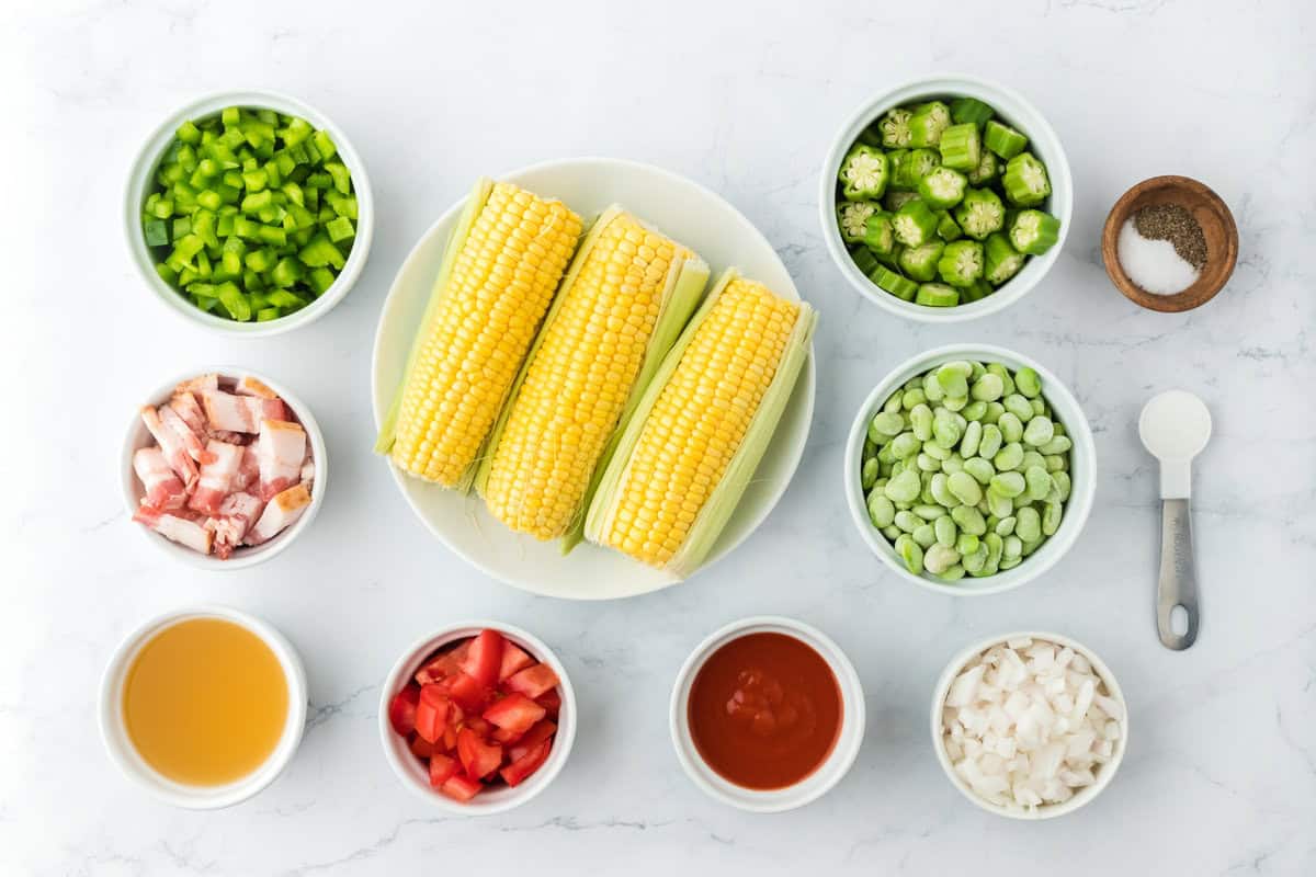 Corn ears, okra, veggies, tomato sauce, bacon, seasonings on a white background