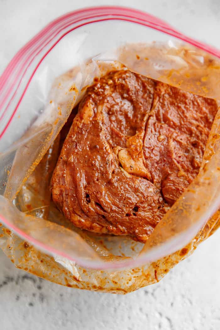 Chipotle marinade with ribeyes soaking in it inside a plastic storage bag
